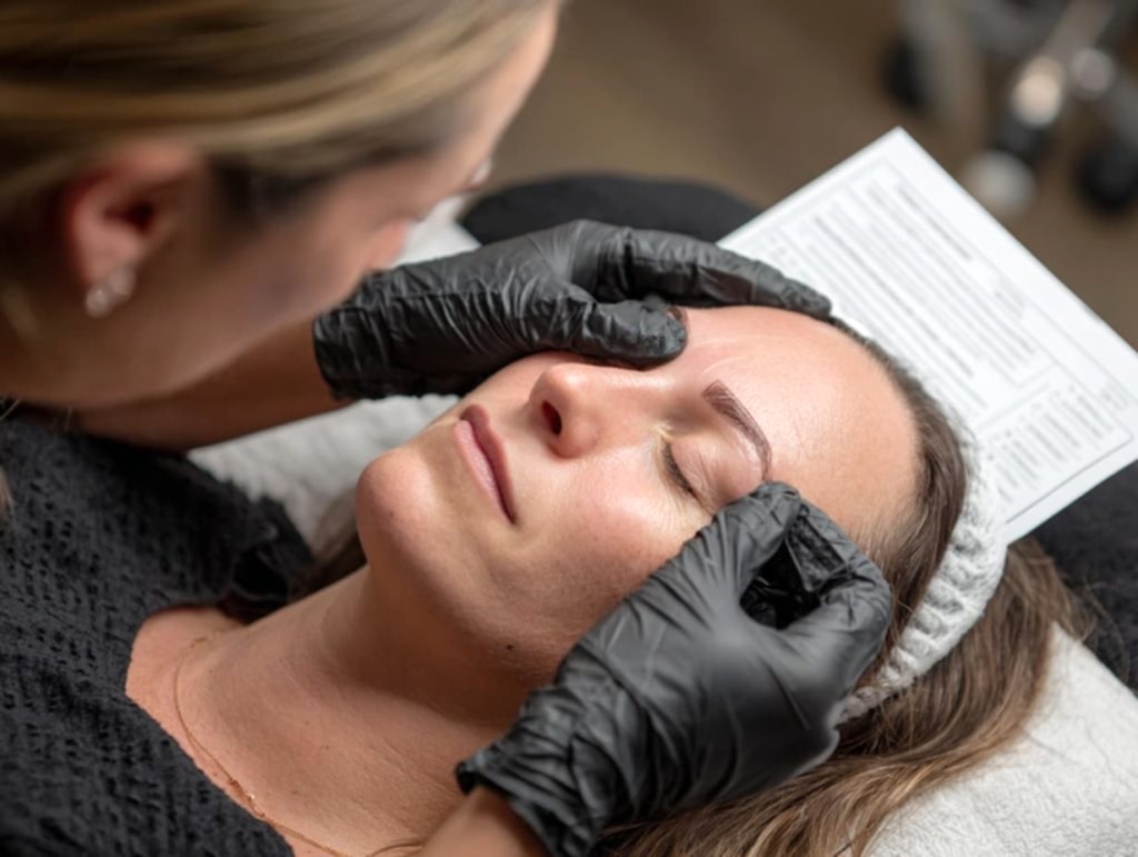 PMU artist explaining microblading aftercare instructions in a clean studio setting
